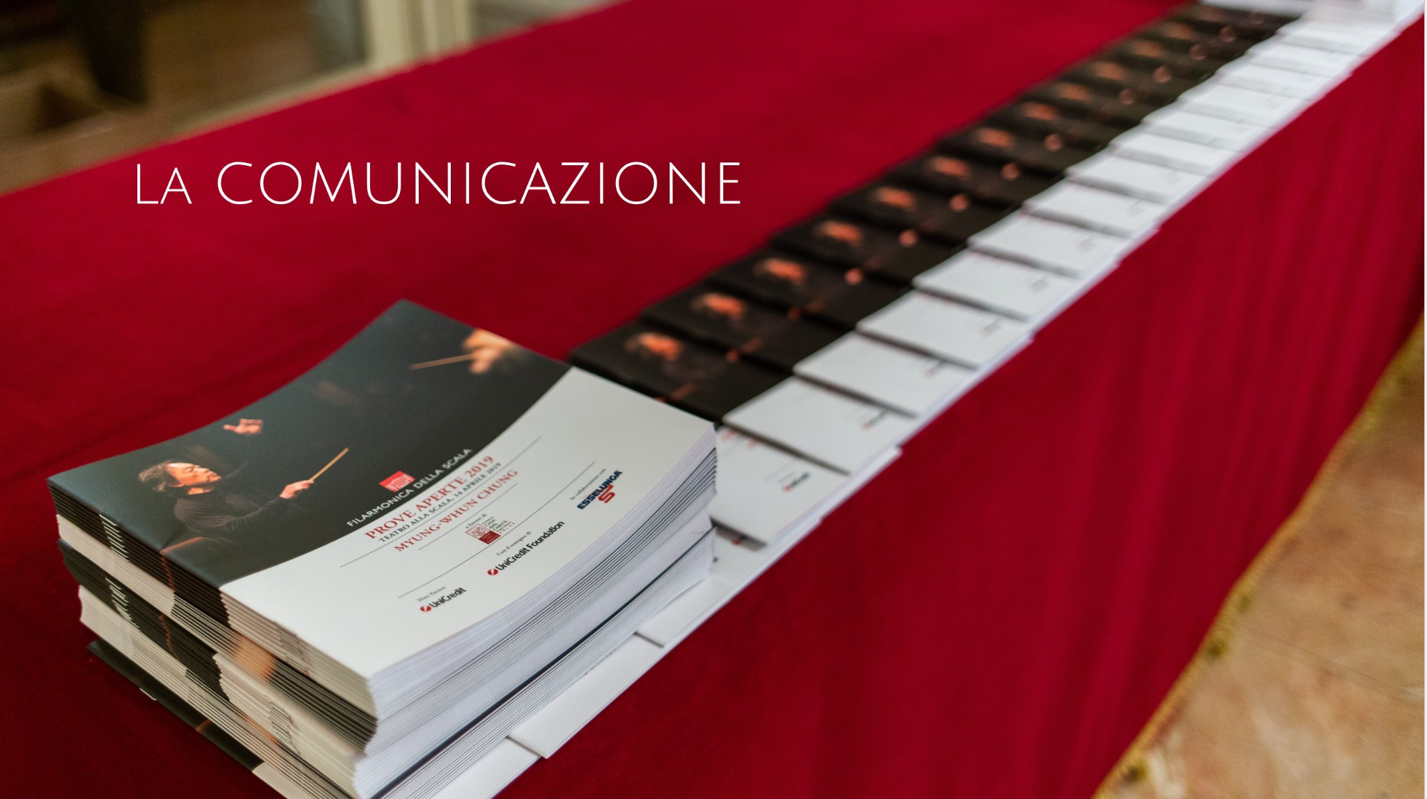 Fotografia intitolata La comunicazione: dépliant e stampati delle Prove Aperte allestiti su un tavolo rosso